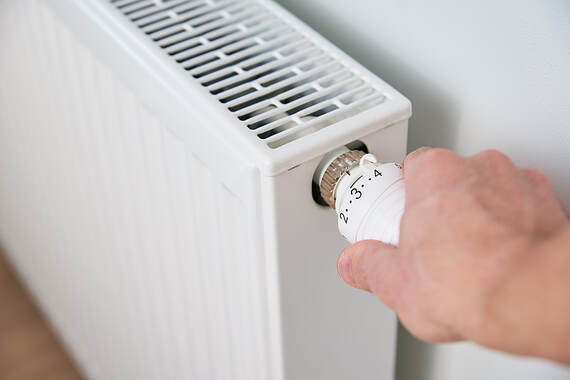 In Greenwich, CT, a man turns the heat radiator knob to control the temperature.