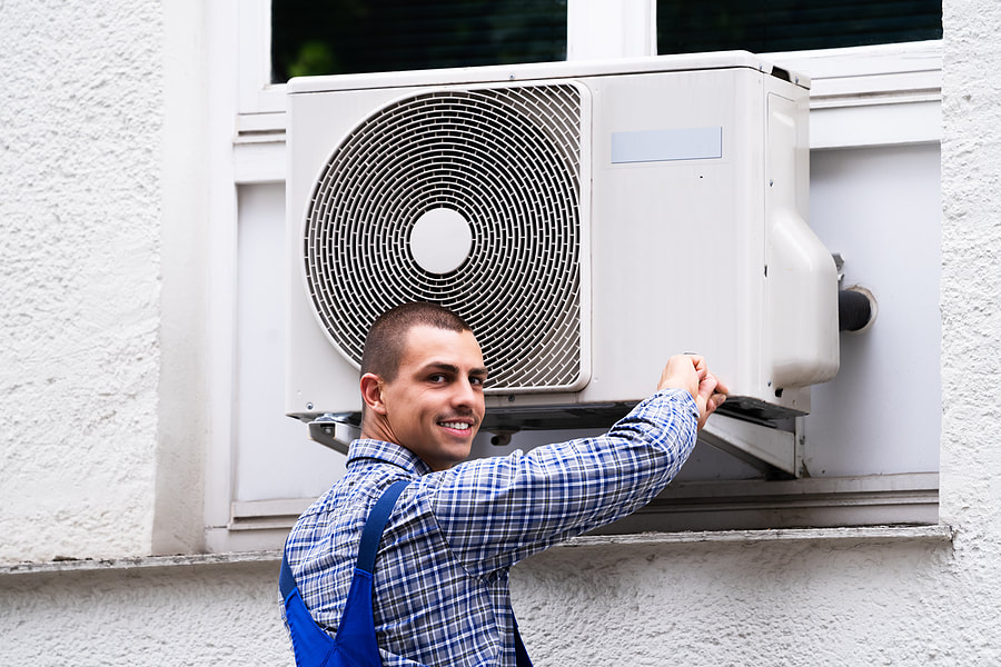In Greenwich, CT, a technician cleans and repairs an air conditioner.